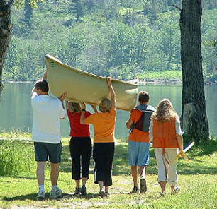 family-carrying-boat-to-lake