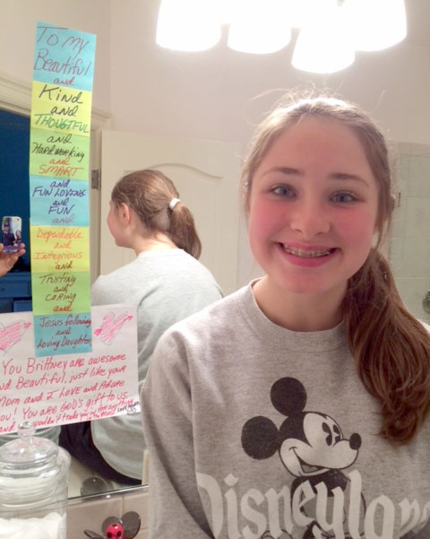 Here’s Brittney sitting next to the messages that her dad, Dan, left on her bathroom mirror. He regularly writes to her now and reports that she never takes them down.