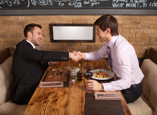 men laugh together while sitting in cafe. two man holding hands