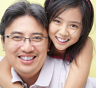 asian-dad-school-age-daughter-hug-over-shoulder-smiles