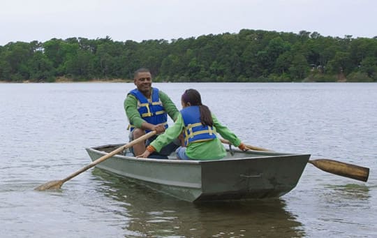 AA dad school age daughter rowing on lake