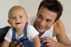 dad playing with infant son smiles