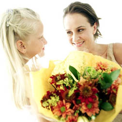 Girl (6-8) Giving a Bouquet of Flowers to a Young Woman