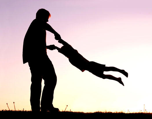 Silhouette of Father Playing with Child Outside at Sunset