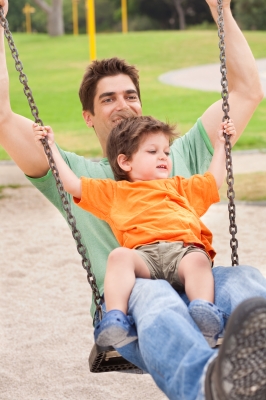 dad swinging with preschool son on lap